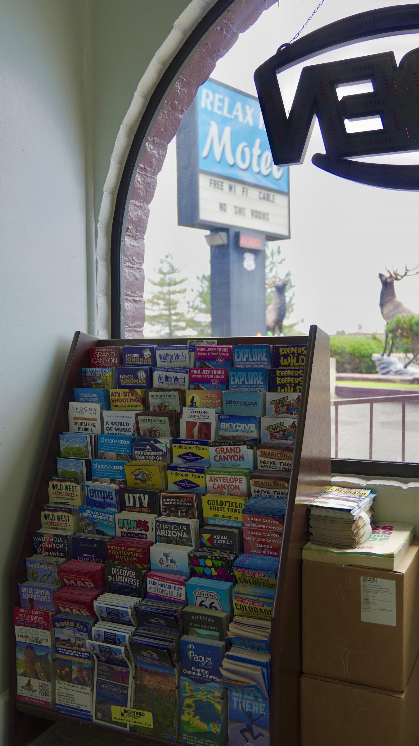 Lobby brochure rack with local attraction guides and a view of the motel sign